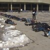 Des personnes son allongées au sol devant l'hôtel de ville de Toronto.