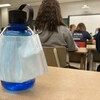 Un masque sur une bouteille d'eau dans une classe. 