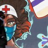 Un homme marche devant une murale représentant une travailleuse de la santé.