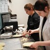 À l'aide d'une fourchette et d'un couteau, deux femmes font la finition sur des pâtés au poulet, debout devant un comptoir.
