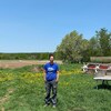 Rébéka Frazer-Chiasson devant un champ et de la machinerie de ferme.