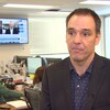 Robert Tétrault est debout dans une salle de nouvelles. 