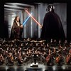 Un orchestre en performance devant un écran géant affichant une scène du film « Star Wars ».