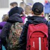 De jeunes élèves de dos dans une cour d'école.