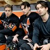 Des comédiens vêtus avec de l'équipement de hockey, sur le banc, dans une chambre des joueurs.