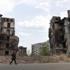 Une femme marche près d'immeubles détruits par les bombardements.