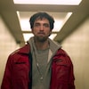 Un homme (Robert Pattinson) dans un couloir beige.