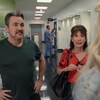 Deux personnes discutent face à une autre personne dans un corridor d'hôpital.