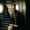 Un homme (Tom Hanks) dans la pénombre pointe un revolver.