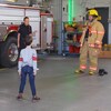 Avec Cynthia Wu-Maheux, les enfants regardent Benoît le pompier qui vient de s'habiller avec son équipement.