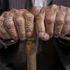 Les mains d'un homme âgé appuyées sur une canne.