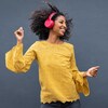 Une femme écoute de la musique en dansant. Elle porte des écouteurs sur ses oreilles.