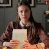 Une jeune femme (Margaret QUalley) assise à un bureau, des lettres entre les mains.