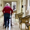 Une personne âgée se déplace avec une marchette dans le corridor d'une résidence privée pour aînés.