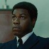 Un jeune homme (John Boyega), en uniforme de policier, regarde vers le haut.