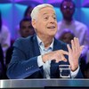 L'homme est assis en studio et montre quelque chose avec ses mains.