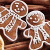 Deux bonhommes de pain d'épices sont décorés avec du glaçage pour faire un visage, des cheveux et un foulard. Les biscuits sont étendus sur des bâtons de cannelle.