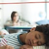 Un enfant qui dort sur son bureau en classe. 