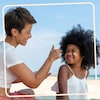 Une mère met de la crème solaire à sa fille.