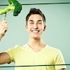 Un adolescent tient fièrement une fourchette avec un brocoli dessus. 