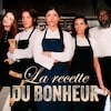 Dans une cuisine professionnelle, quatre cuisiniers et une influenceuse se tiennent côte-à-côte. L'un laisse tomber des billets de 100$ au sol, l'autre prend un égoportrait.