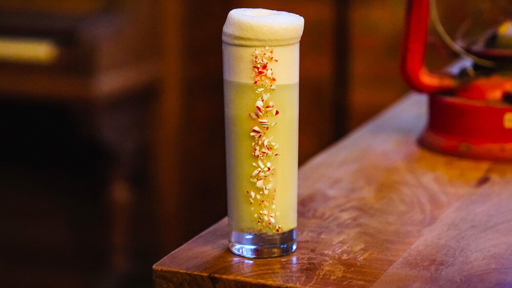Un cocktail dans un verre décoré de morceaux de canne de bonbon.