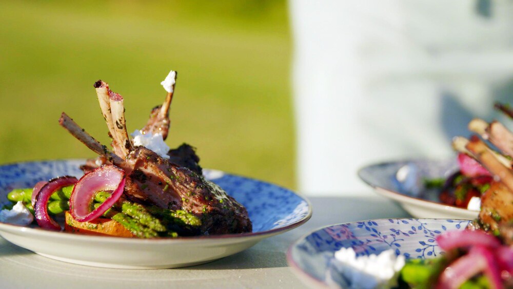 Des côtelettes d'agneau grillées dans une assiette avec des légumes.