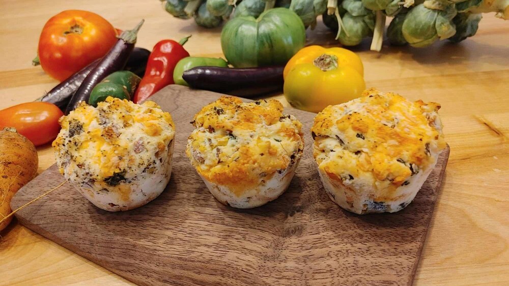 Des muffins aux légumes et au bacon sur une planche en bois.