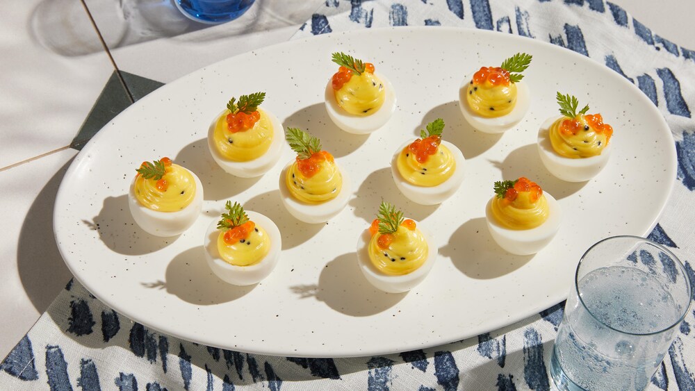 Des œufs mimosa avec du caviar en garnitures sont disposés dans une assiette de présentation.