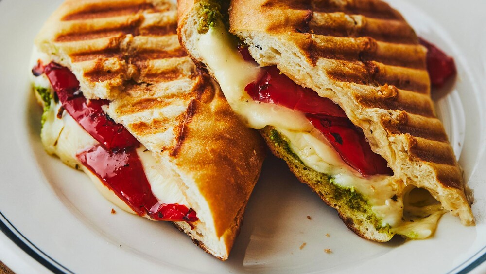Dans une assiette, un panini à l'italienne tranché au milieu. 