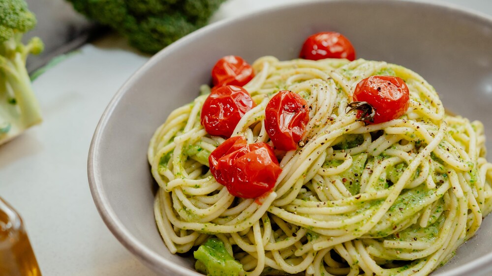 Un plat de spaghettis et sauce au brocoli, avec des tomates cerises confites.
