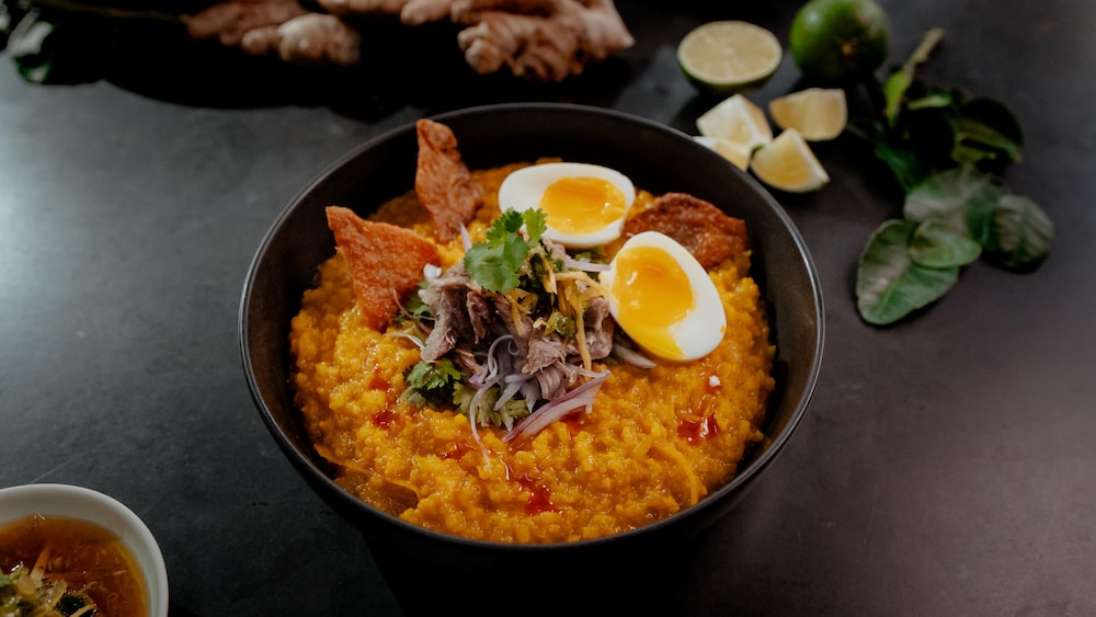 Un bol de porridge de riz au canard confit et au gingembre, garni d'oeufs.