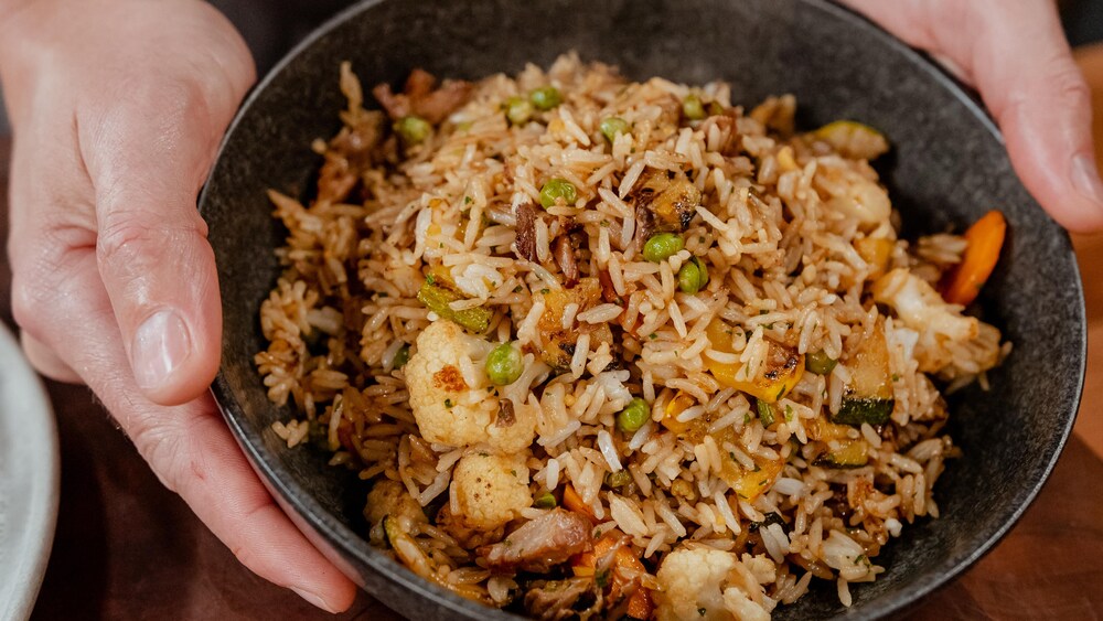 Un bol de riz frit vide-frigo, avec de la viande et des légumes.