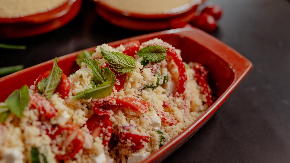 Un plat de salade de couscous aux légumes garnie de menthe fraîche.