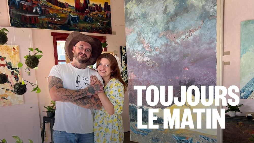 Couple devant une série de tableaux dans une galerie d'arts dans le village Western de St-Tite. 