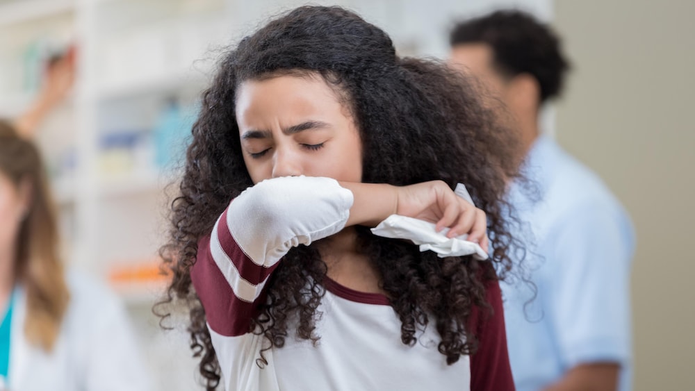 Une préadolescente tousse dans son coude.