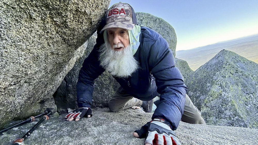 Dale Sanders avance à quatre pattes sur des rochers.
