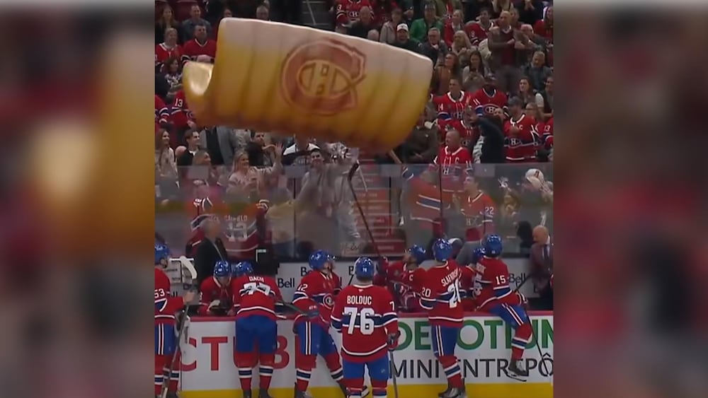 Un pain à hot-dog géant gonflable est tenu à bout de bras par des personnes dans les estrades du Centre Bell.