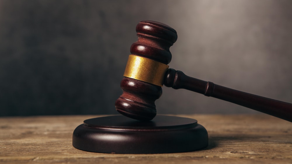 Un maillet de juge en bois sur fond brun.