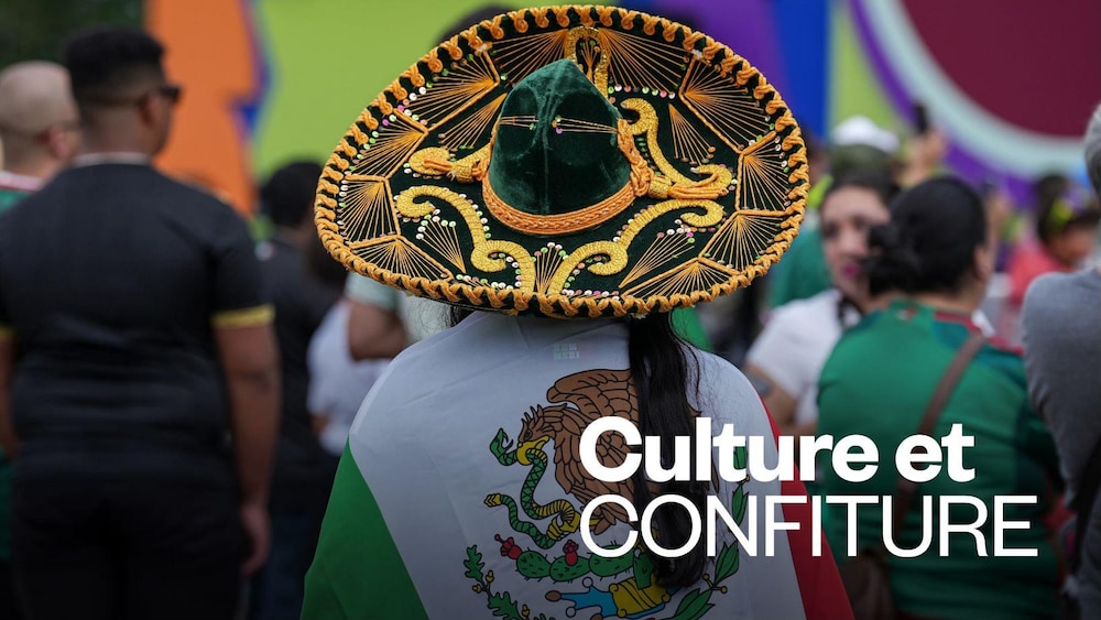 Une partisane de l’équipe du Mexique de dos avec un sombrero et un drapeau mexicain sur les épaules.