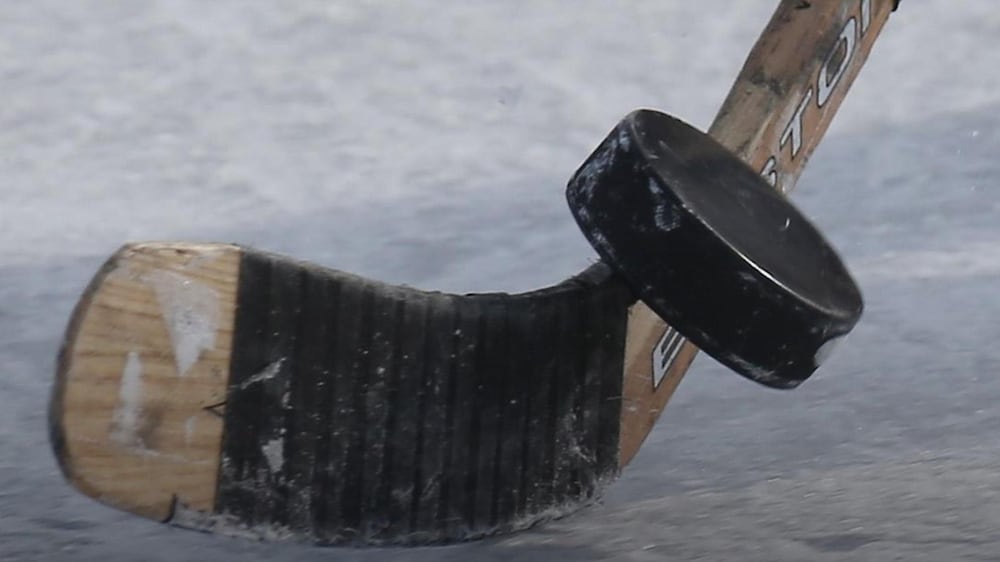 Un bâton de hockey qui frappe une rondelle sur une patinoire.