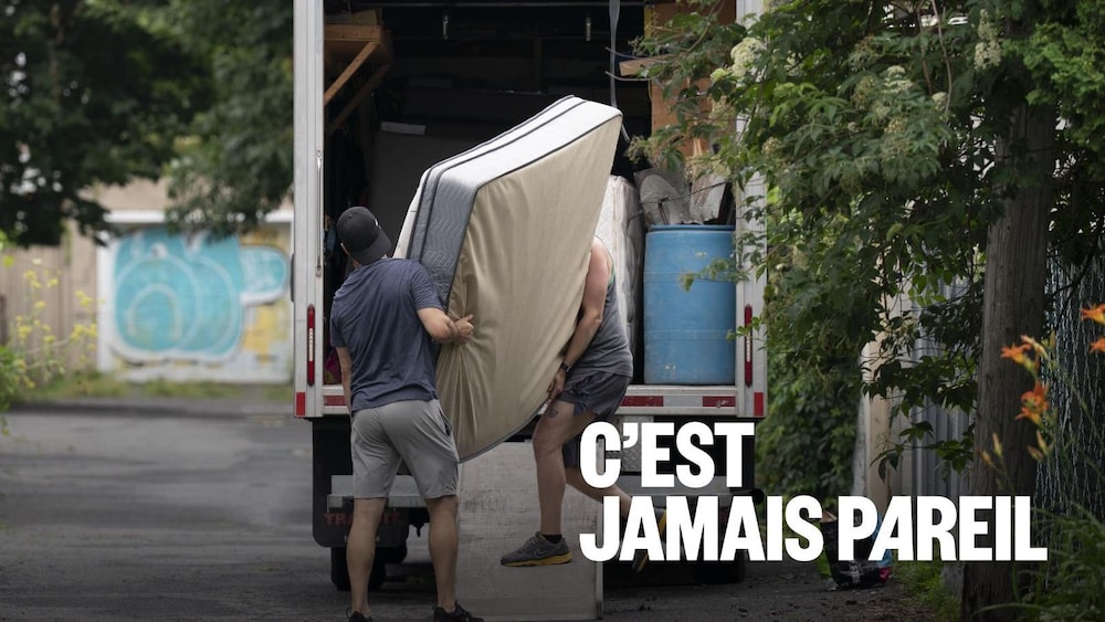 Deux personnes transportent un matelas vers un camion de déménagement.