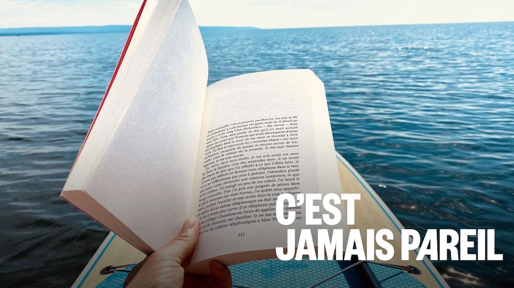 Un lecteur assidu, installé sur une planche à pagaie, est plongé dans un roman.