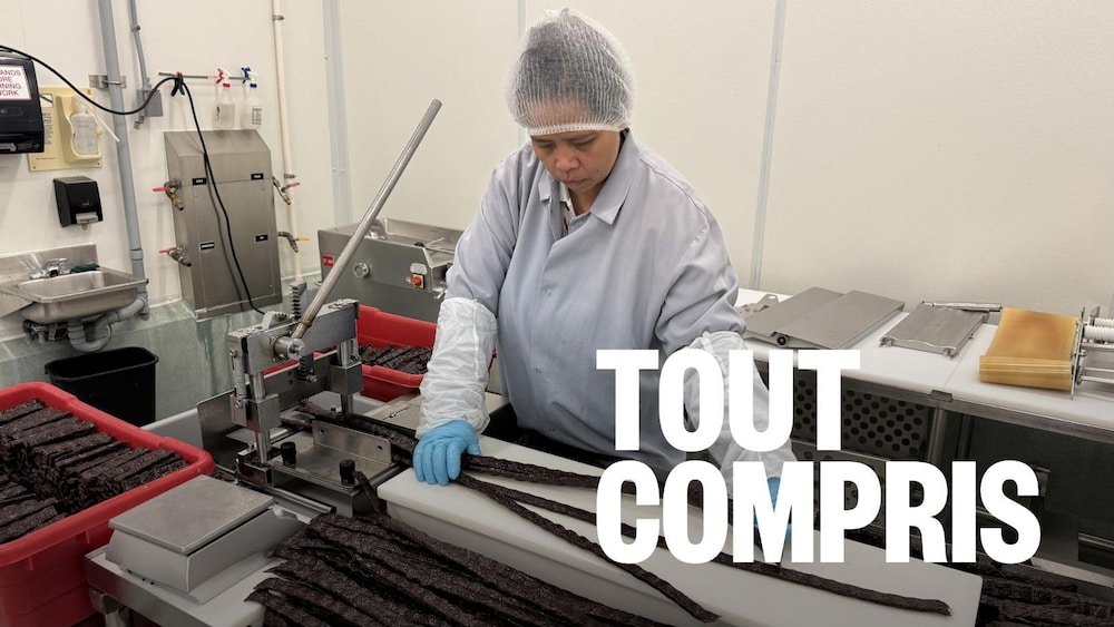 Une employée procède à la découpe du jerky de bison. De longues lannières sont coupées à l'aide d'une guillotine.