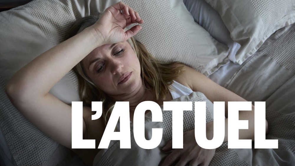 Une femme, l'air fatiguée, couchée sur un lit