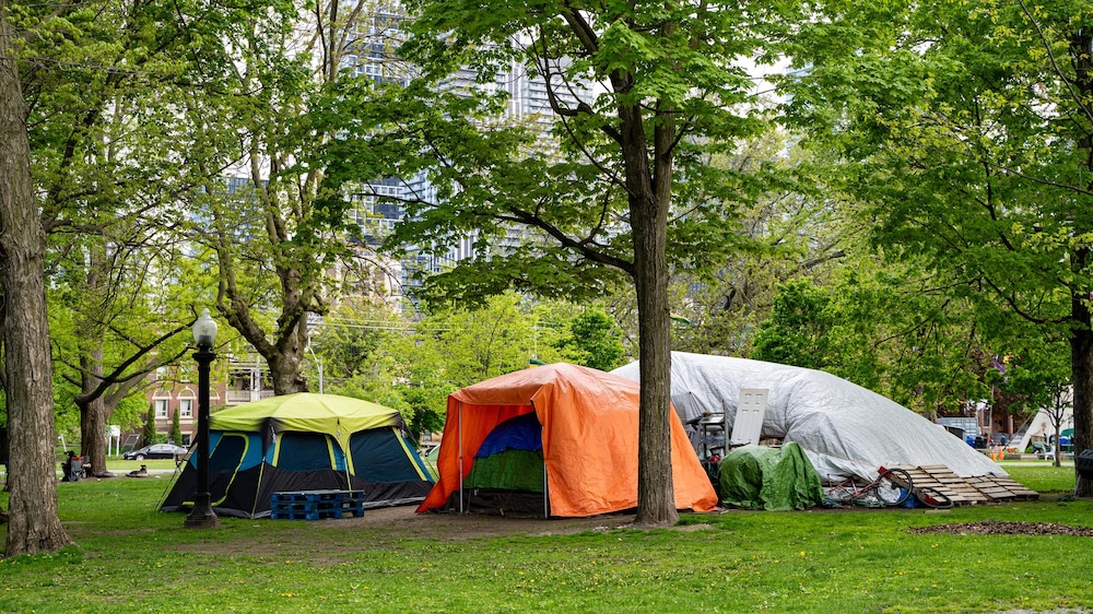 Des tentes installées dans un parc en ville.