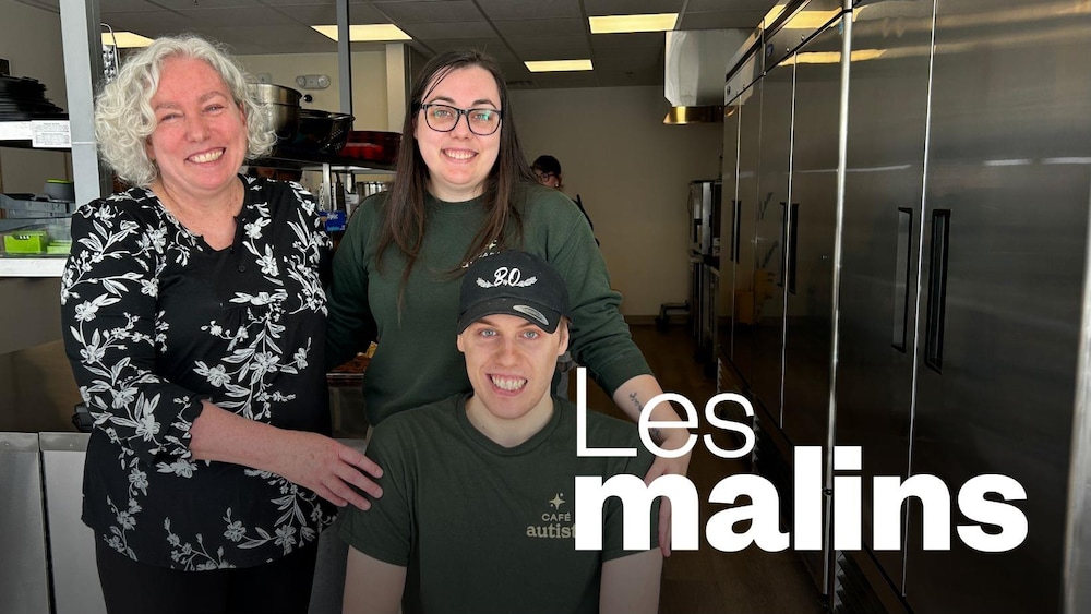 Deux femmes et une homme qui posent dans la cuisine d'un restaurant.