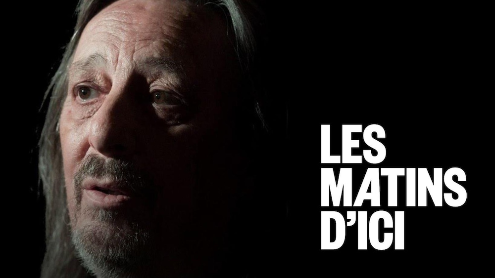 Photo du chanteur avec une moitié du visage dans l'ombre, sur fond noir.