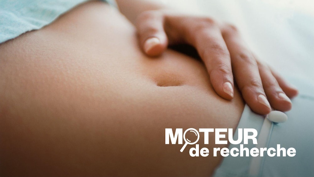 Une personne a le ventre dénudé, la main posée près du nombril.