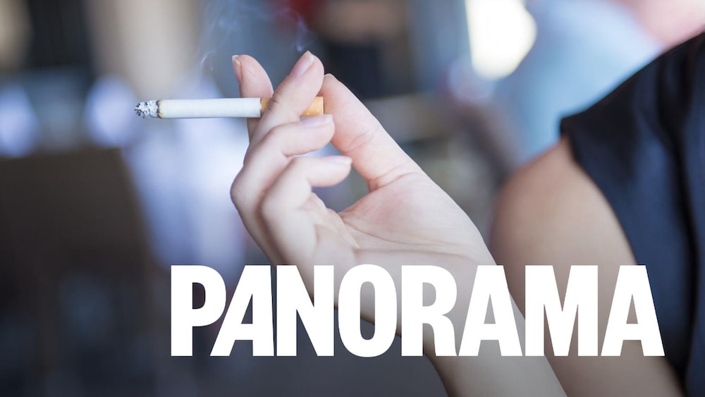 Une femme tient une cigarette allumée.